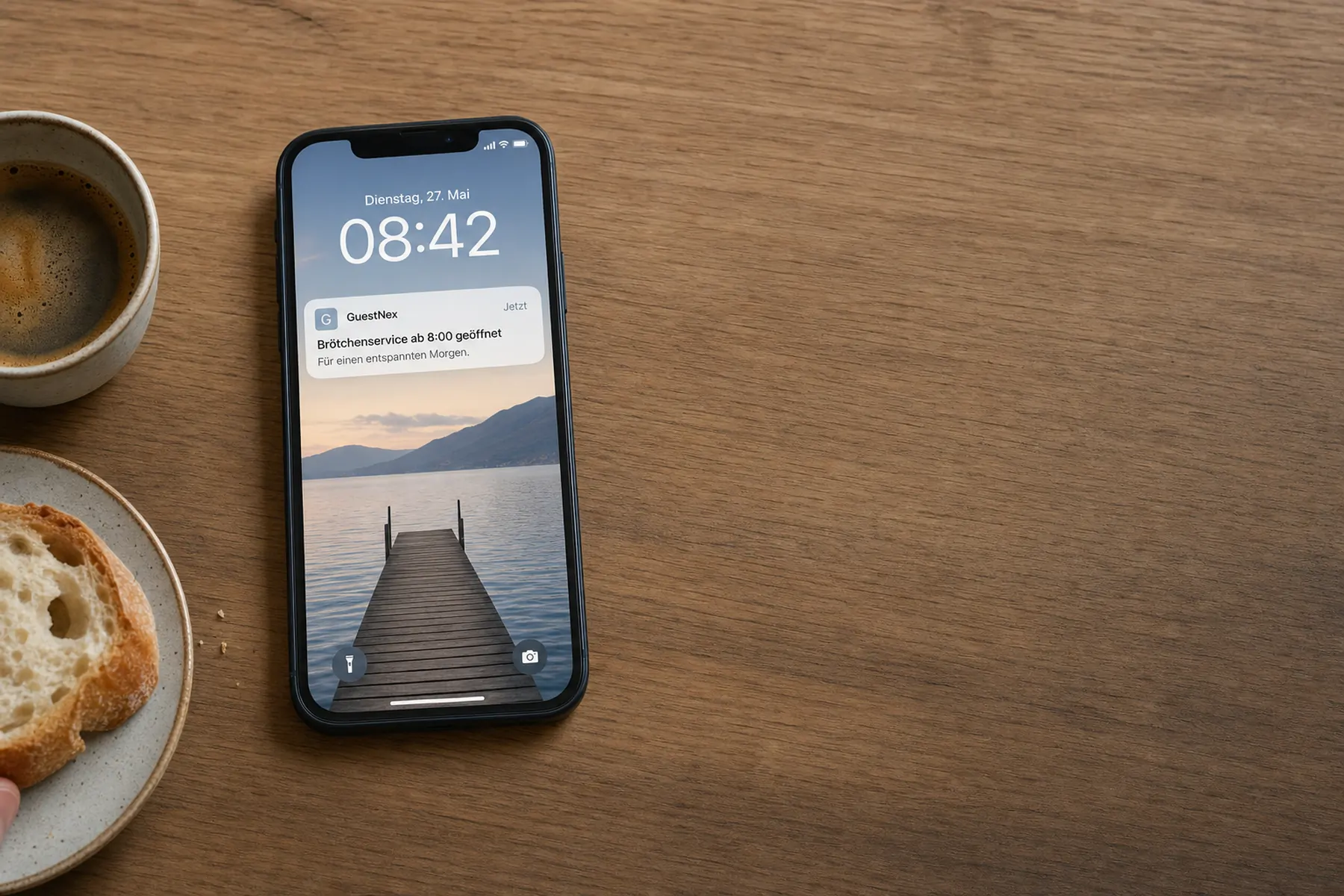 Frühstückstisch von oben mit Smartphone, das eine GuestNex-Push-Nachricht zu einer Abendveranstaltung anzeigt